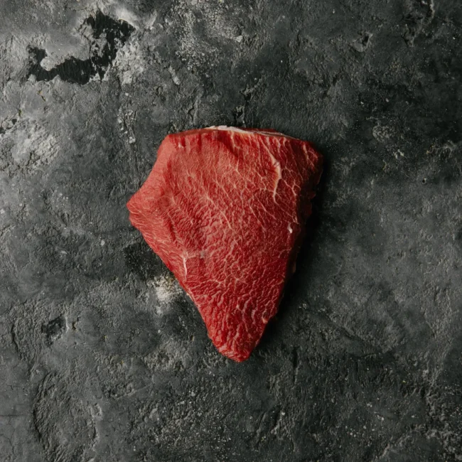 Raw steak on dark surface