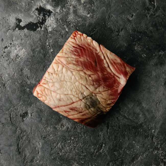 Raw beef brisket on dark background.