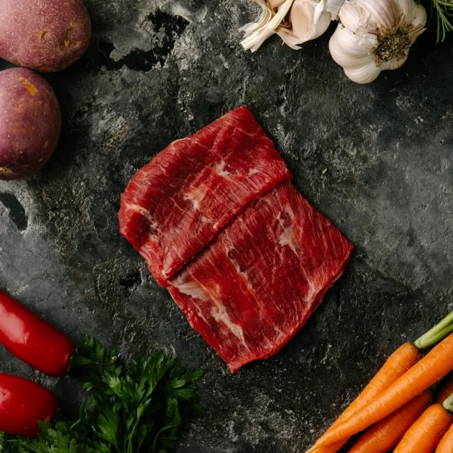 Raw beef with vegetables on dark stone surface